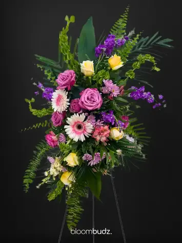 Mixed color standing spray with purple pink and yellow blooms by bloombudz in Paragould