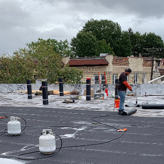 Roofing contractors on a flat roof for a new roof replacement.