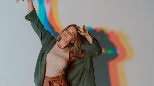A woman dancing with colored silhouettes behind her.