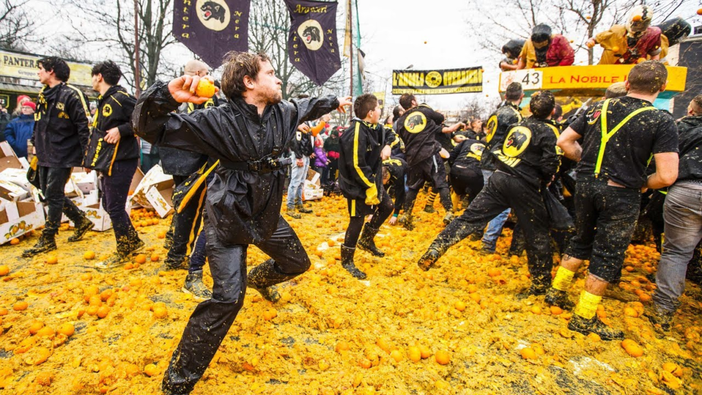 Several people throwing oranges at each other in the historic town of Ivrea, in northern Italy, which hosts the “Battle of the Oranges” festival.
