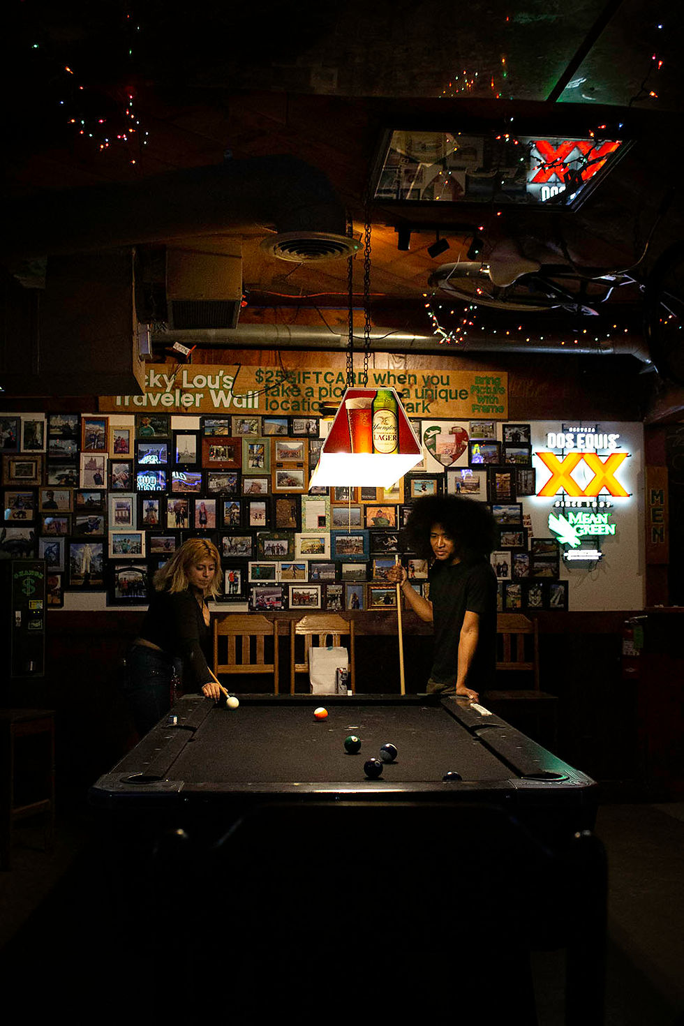 DIFFUSED AND ARTIFICIAL. A young couple plays a serious game of pool under the neon signs of Lucky Lou’s Bar in Denton, Texas, on Sunday, Sept. 14, 2025. ©2025 Rubyanne Moley/SMU