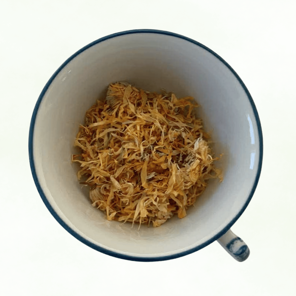 Calendula, loose dried flowers in a teacup, bird's - eye view