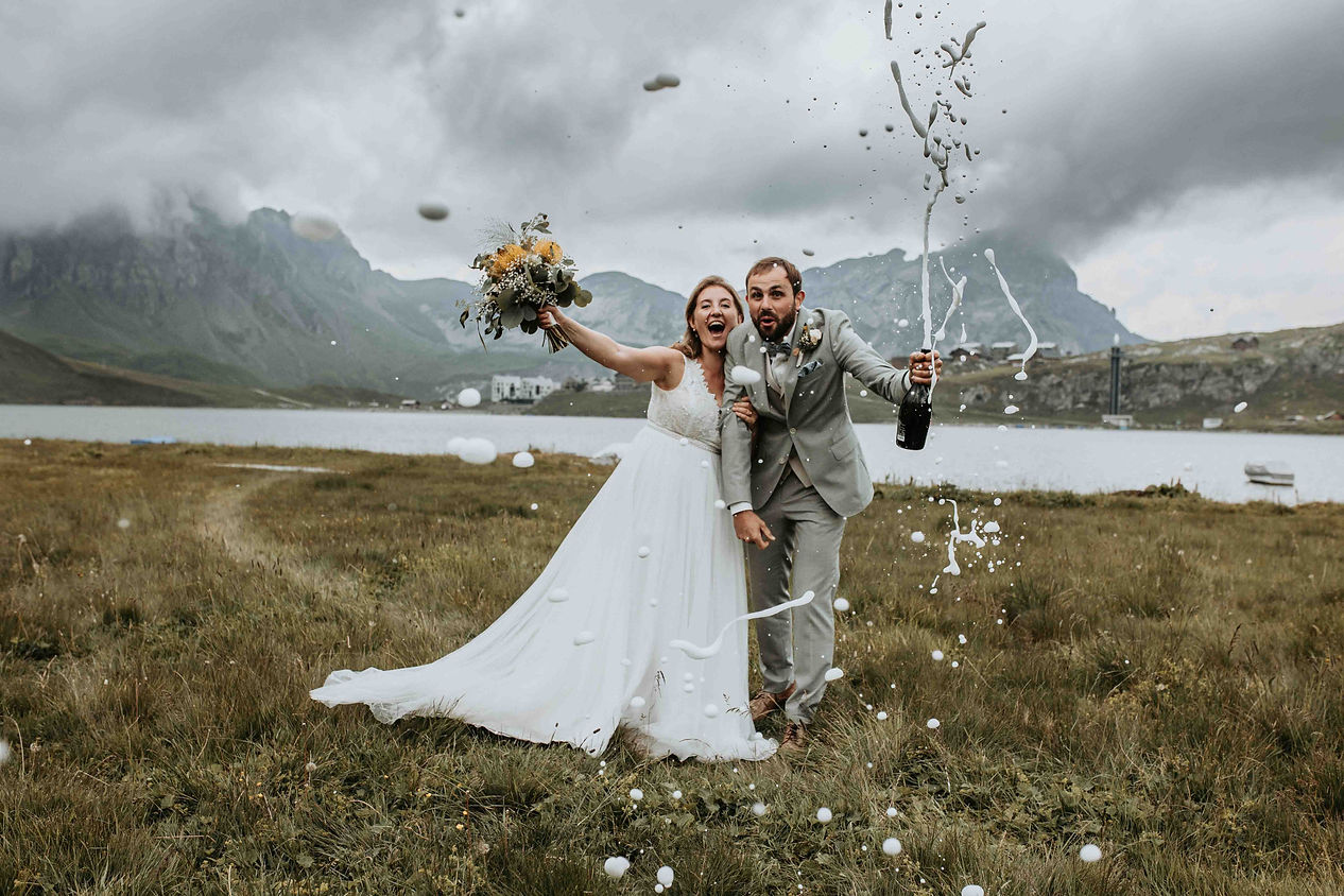 Brautpaar in Melchsee Frutt stoßen mit Champagner an und knallen den Korken – Hochzeitsfotograf Aargau