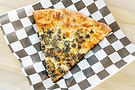 Pizza slice with herbs and cheese on checkered paper