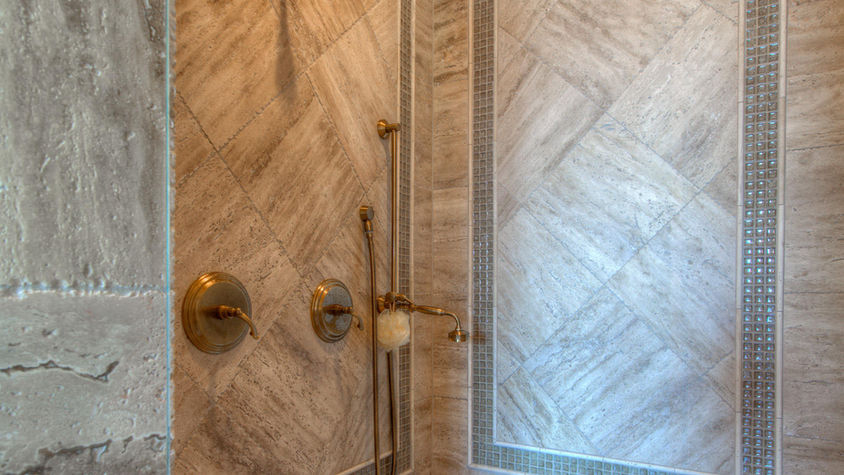 Elegant shower with marble tile, gold fixtures, and built-in bench. For Builders.