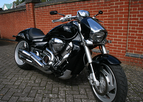 Black Suzuki M109R motorcycle parked by brick wall
