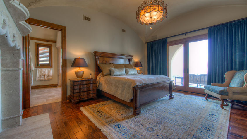Luxury bedroom with king size bed, rug, and balcony access.