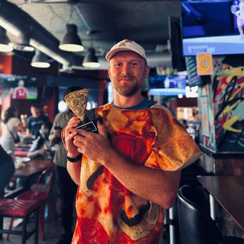 Man in pizza shirt holding pizza slice award