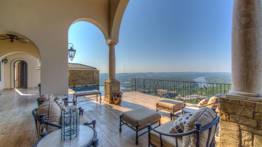 Outdoor patio with seating overlooking a scenic view under a bright sky.