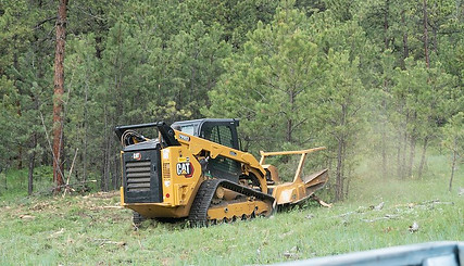 Skid steer with an ambusher attachment.