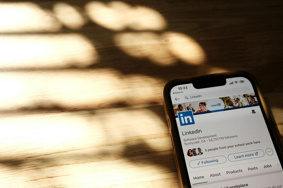 Smartphone showing LinkedIn profile on a wooden table with soft shadows. Screen displays user info and options, creating a professional mood.