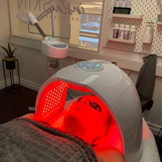 After renovation: Client receiving red light therapy under a specialized LED light device in a cozy, softly lit treatment room at the InstaSkin salon.