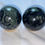 Thumbnail: Two polished stone spheres on a white surface, with swirls of green and black