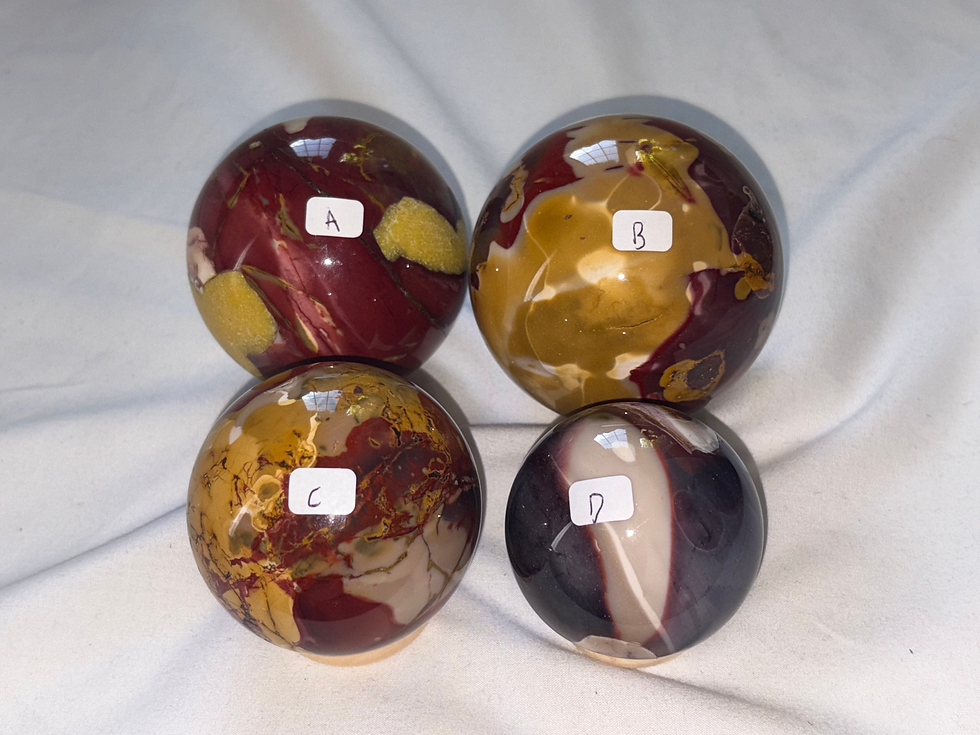 Four stone spheres with visible text A, B, C, and D, displayed on white fabric.