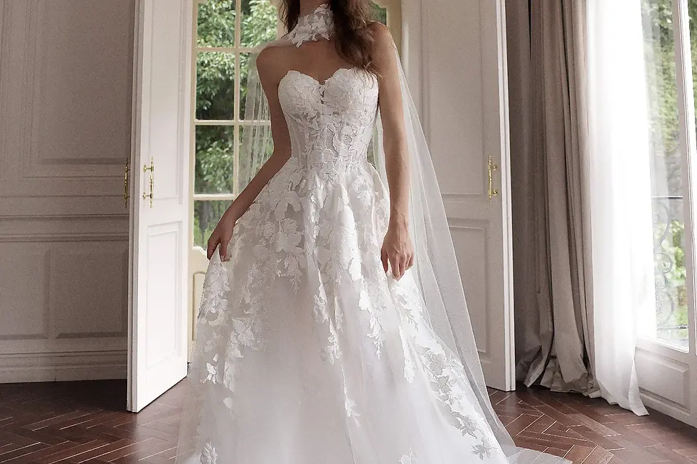A romantic A-line bridal gown with layered tulle and subtle 3D floral embroidery, photographed in an outdoor garden with blooming white roses.