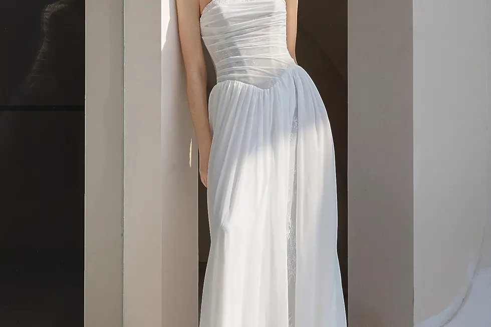 Eine glückliche Braut in einem fließenden Chiffon-Brautkleid läuft durch einen grünen Schlossgarten, während das Kleid im Wind weht.