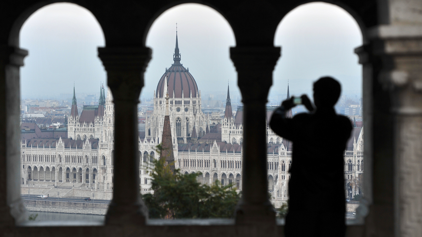 View of Budapest Parliament through Fisherman’s Bastion with tourist silhouette – perfect stop for whisky lovers at Tölgyfa Hordó Pub.
