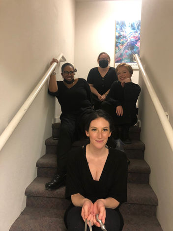 Four employees sitting on stairs smiling at the camera.