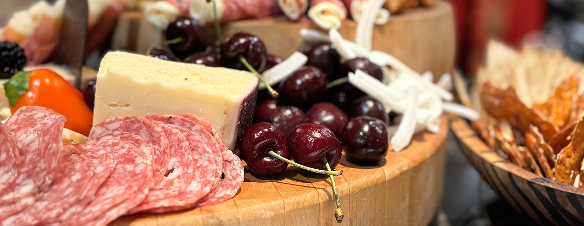 Appetizer board with salami, cheese, fresh cherries, almonds, and crackers.