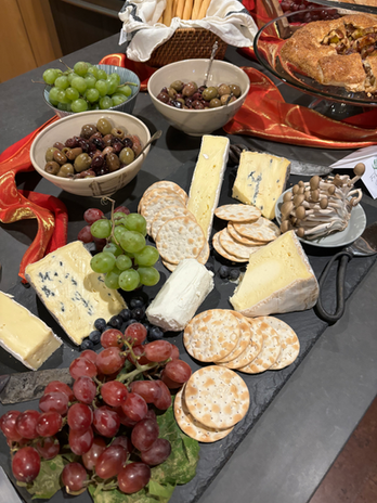 Variety of cheeses, crackers, grapes, olives, and mushrooms on board.