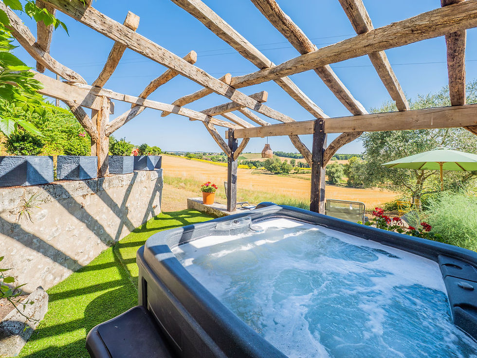 Private hot tub beneath a traditional timber pergola overlooking the Charente countryside at Carmagnac.
