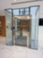 Modern glass platform lift in a commercial lobby, suitable for LOLER inspection and lift compliance under UK regulations.