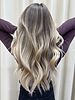 Cool-toned blonde balayage with soft waves, featuring bright highlights and a smooth, blended finish.
