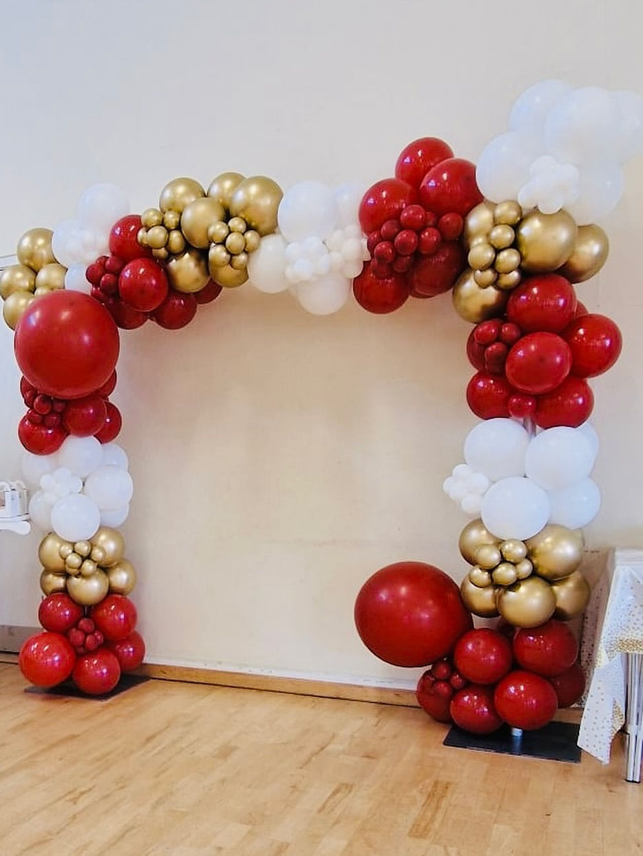 Red, gold and white balloon arch installation for wedding or event backdrop.