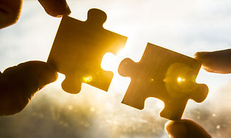 two hands trying to connect couple puzzle piece with sunset background. Jigsaw alone woode