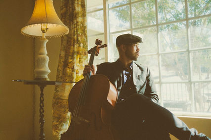 cellist poses next to window with cello