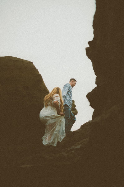 Couple climbing rocks to beach cliff in Southern California, San Diego