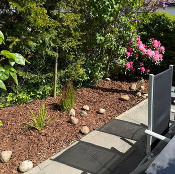 Blick auf die Bepflanzung einer Terrasse mit Gräsern und pink blühender Rhododendron