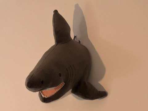 ein halber Hai als Stofftier auf einer Wand