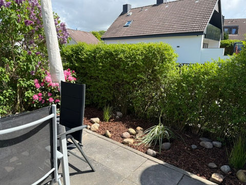 Terrasse mit Sichtschutzhecke, Blumen, Gräser und Sonnenschirm