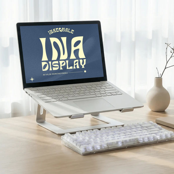Bærbar PC på stativ, eksternt tastatur. Skjerm: 'INA DISPLAY'.