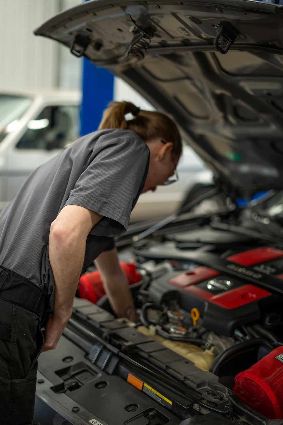Female with hand in lower part of nissan 370z nismo motor. Red motor cover,