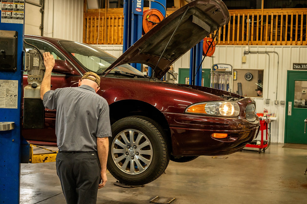 Male lifting maroon buick on yellow lift. Upstairs include unpainted fence.