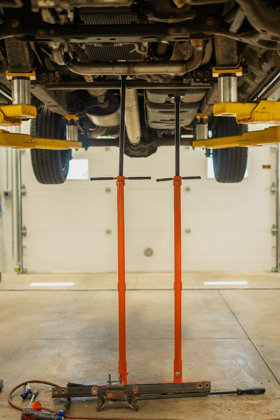 Two small orange lifts hlding up mtal piece on underside of vehicle.