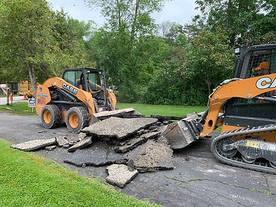 Asphalt resurfacing process showing removal of failed pavement sections using heavy equipment on a roadway.