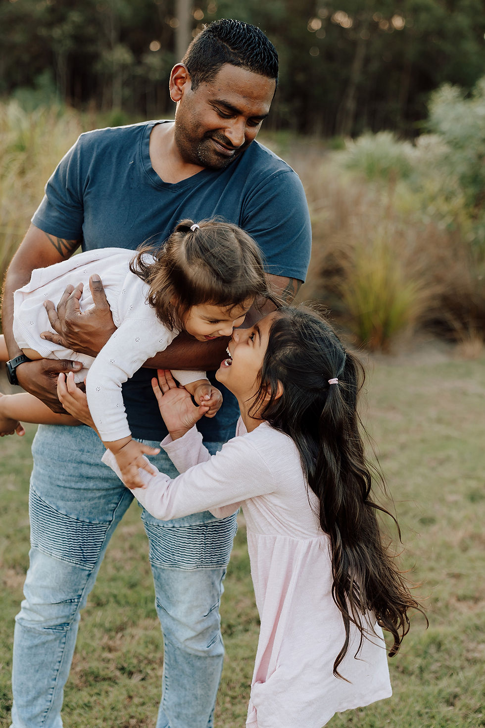Two sisters embracing eachother as their father watches on
