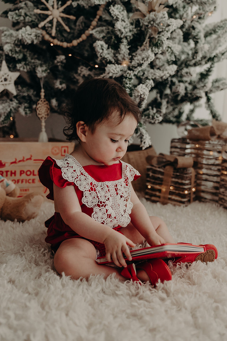 a baby sitting on the floor reading a book