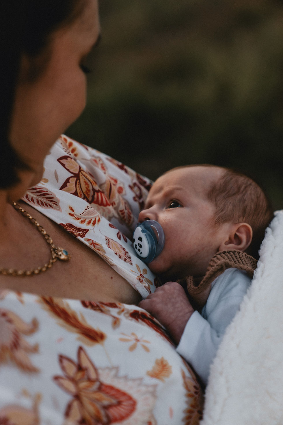 Newborn baby staring into mothers eyes while sucking on a pacifier