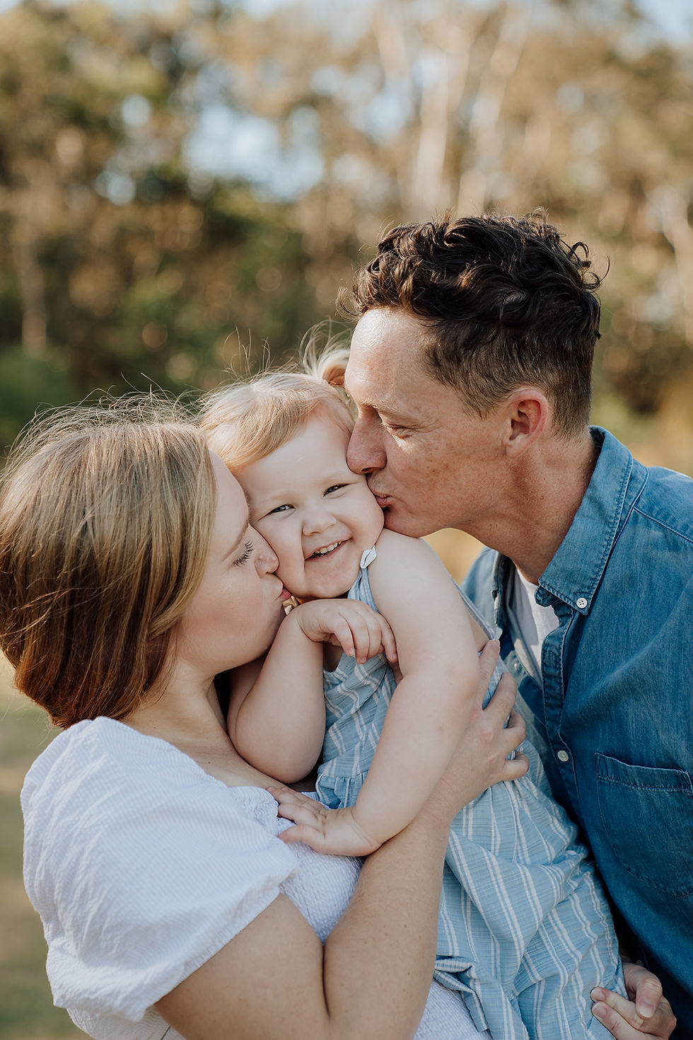 Brisbane family kissing their child on the cheek while having photo taken