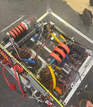 The Robot, now with reinforced shooter, intake, as well as newly sorted wires, sits on the floor while being actively worked on.