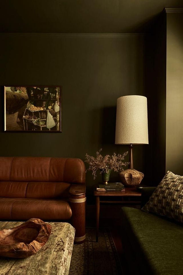 canapé en cuir mur vert table en marbre avec une lumière d'ambiance à poser sculpturale pour un salon cosy et réconfortant 