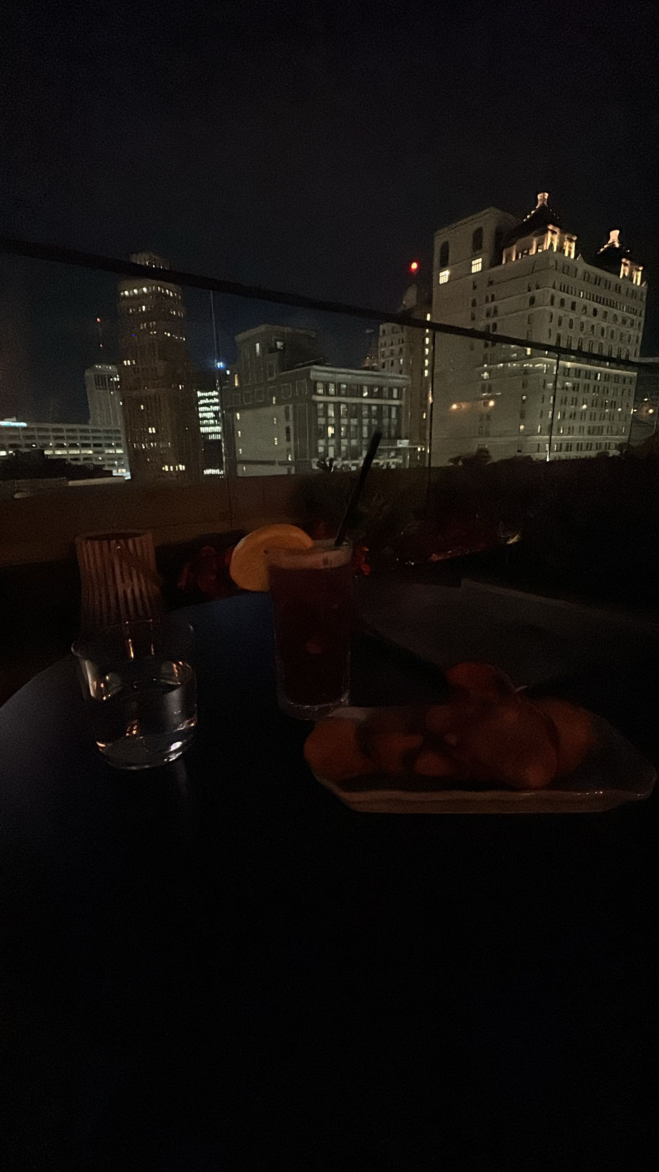 Rooftop of bar with food and drink and city in background 
