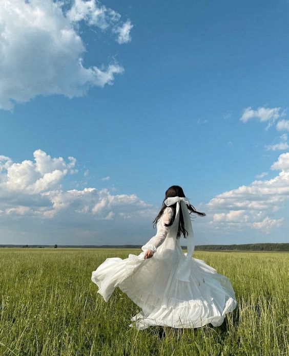 girl in long white dress in field on sunny day