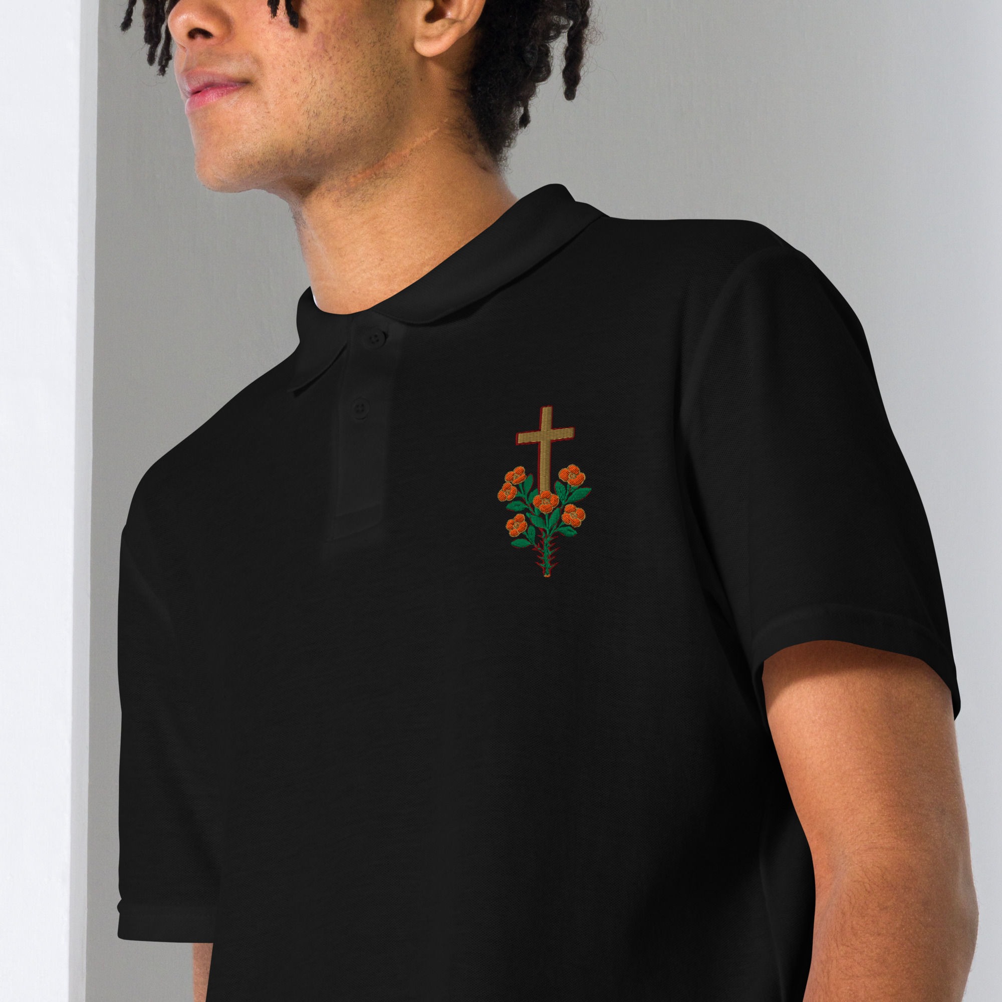 Man wearing black polo shirt with cross and rose embroidery. 3FoldLoveCo