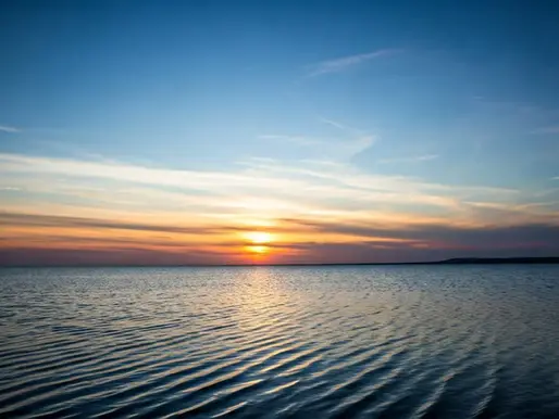 sunrise with blue skies over the water