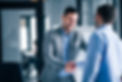 two-smiling-businessmen-shaking-hands-while-standing-in-an-office.jpg